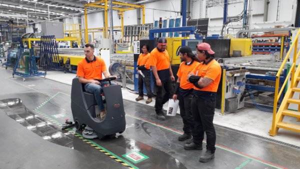 factory workers watching floor scrubbing machine demonstration