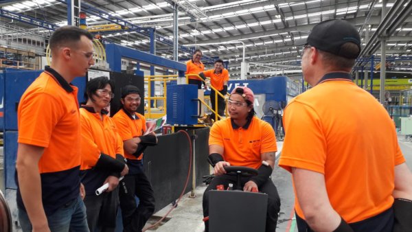 factory workers standing around in a factory for machine demonstration