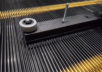 Close up of vacuum floor tool bristles combing the tread of an escalator step